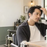 鏡でM字の生え際を確認する男性とシャンプーボトルのイメージ