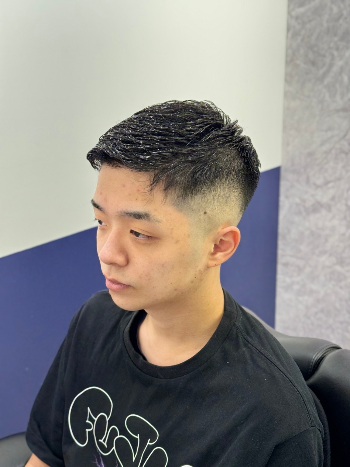 直毛にコテパーマをかけ、額を出した前髪とハイフェードを合わせた前斜めの仕上がり